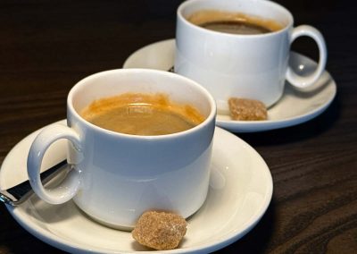 Two Americanos in cups and saucers with a raw sugar cube
