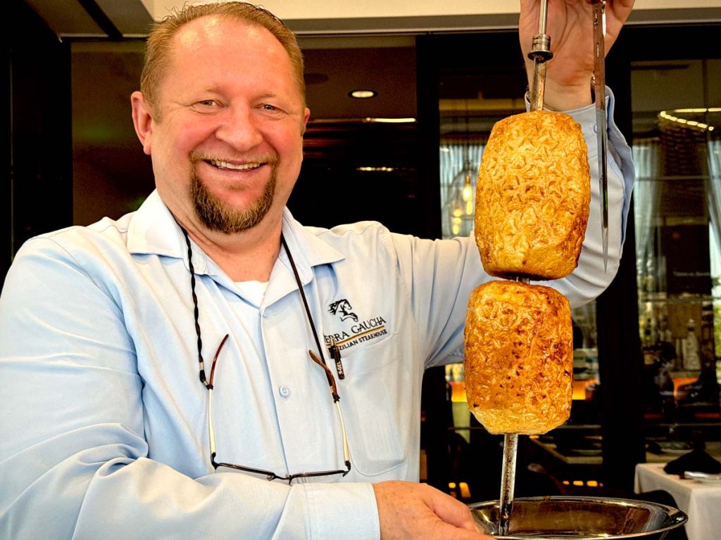 Alceu Pressi, managing partner with grilled pineapple (abacaxi)